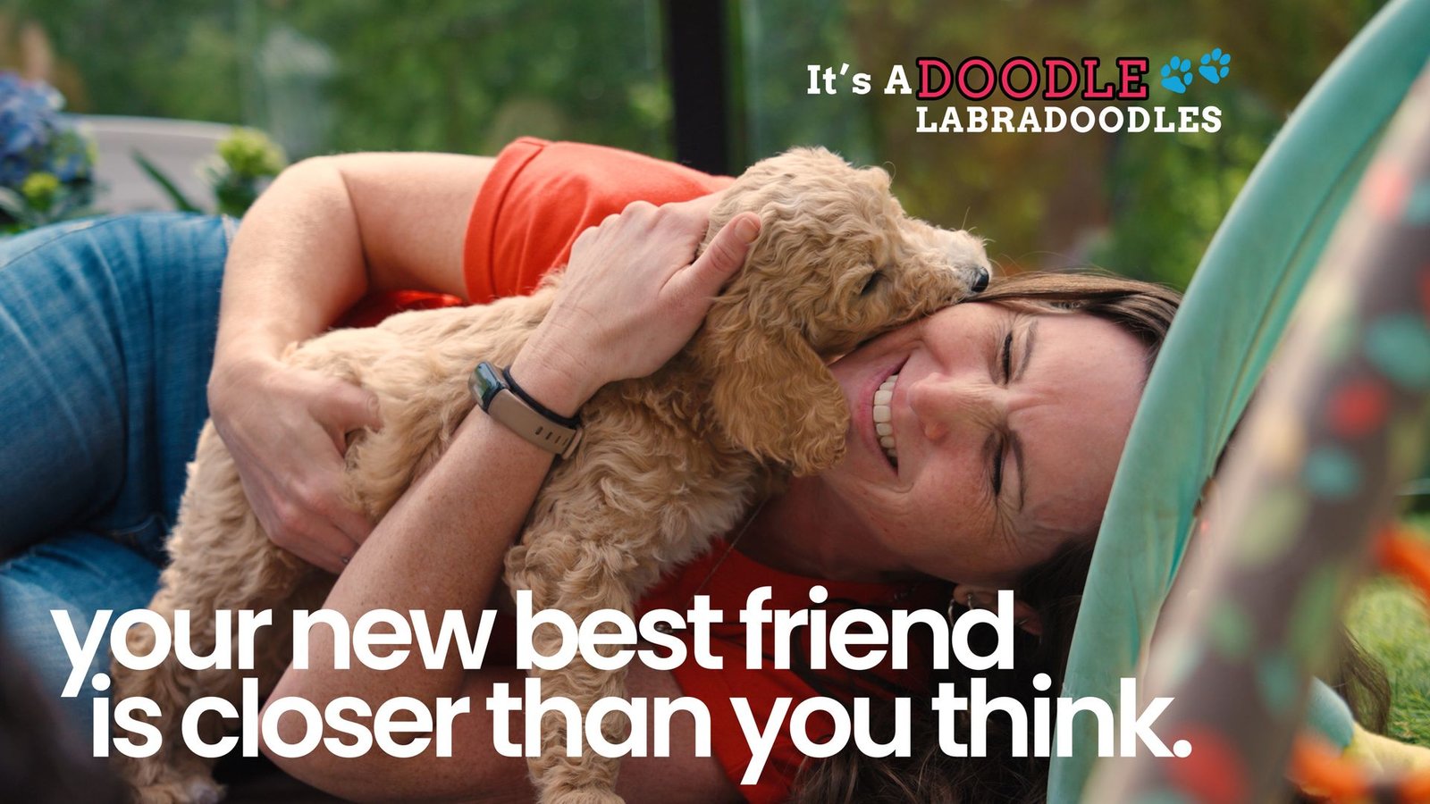 A frame from the It's A Doodle brand video: a woman hugging a Labradoodle puppy, with the It's A Doodle Labradoodles logo and the line 'your new best friend is closer than you think'