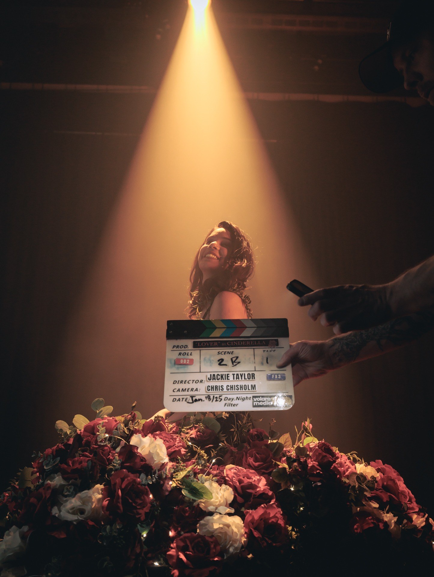 A Volare Media film slate held in a spotlight on a music video set